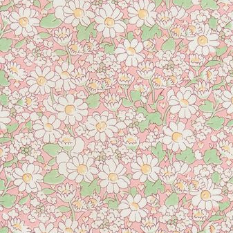 A close-up of a pink floral fabric or wallpaper pattern with white daisy-like flowers, green leaves, and small yellow centers, shown with a gold metal ruler along the right edge for scale.