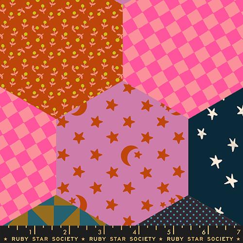 Patchwork fabric with various patterns including stars, checkered, and floral designs on a ruler.