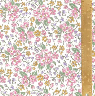 A close-up of a floral fabric pattern featuring pink, yellow, and purple blossoms with green leaves on a white background, with a wooden ruler running vertically along the right side for scale.