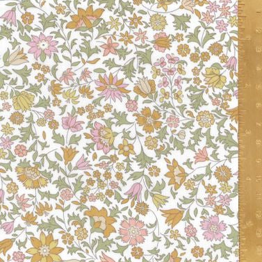 A close-up of a floral fabric pattern with small pink, yellow, and orange flowers on a white background, shown with a gold metal ruler along the right edge for scale.