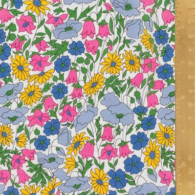 A close-up of a floral fabric pattern with yellow daisies, pink bell-shaped flowers, blue flowers, and light blue clouds on a white background, with a wooden ruler along the right edge for scale.