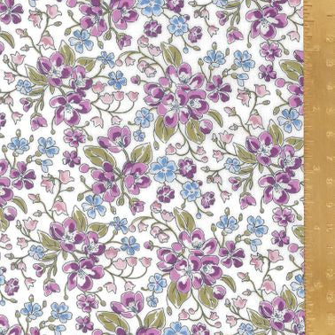 A close-up of a floral fabric pattern with purple, blue, and pink flowers on a white background, shown with a wooden ruler along the right side for scale.